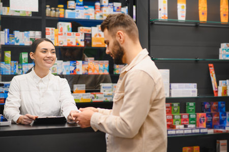 Pharmacist smiling, giving a customer medicine at the pharmacy counter. Patient purchasing prescription drugの写真素材