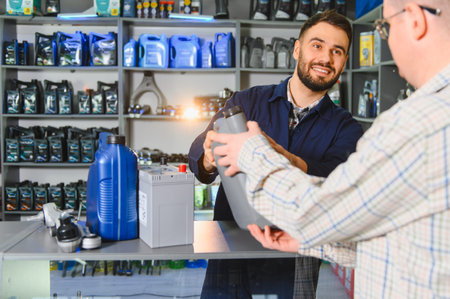 Smiling auto parts store employee presenting engine oil to a customer, showcasing good service and vehicle maintenance itemsの写真素材