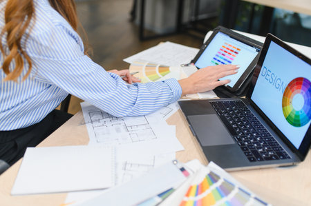 Professional designer working on architectural blueprints and selecting color palettes for interior...