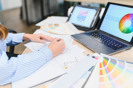 Creative professional or interior designer creating architectural plans, using laptop, tablet, and...