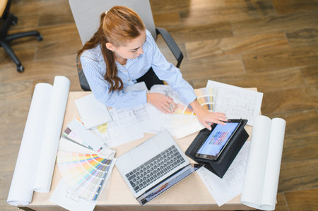 Female professional designer selecting colors on a tablet and color palette, drawing architectural...