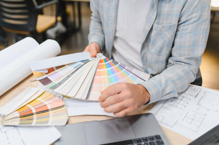 Designer working on creative plans, selecting paint swatches from a color fan for home interior designの写真素材