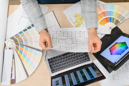 Professional hands holding a blueprint, creating an interior design project with color swatches,...