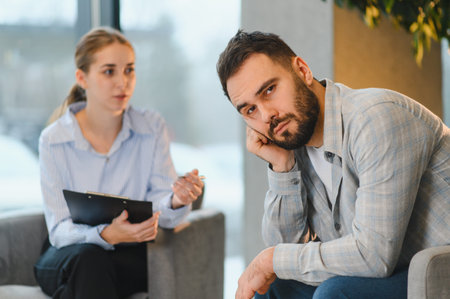 Man feeling sad and stressed, receiving support from a female psychologist during a therapy session...