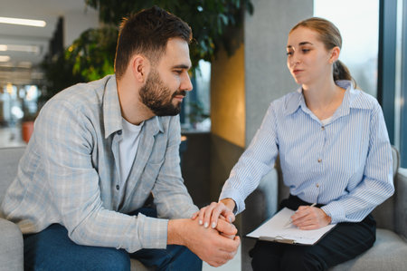 Man finding support during a psychological therapy session, discussing mental health concerns with a professional counselorの写真素材