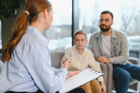 Female psychologist providing counseling session to father and young boy. Family seeking professional psychological help and supportの写真素材