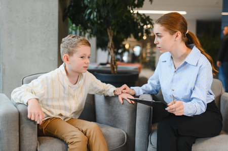 Psychologist offering comfort and guidance to a young boy during a therapy session, focusing on...