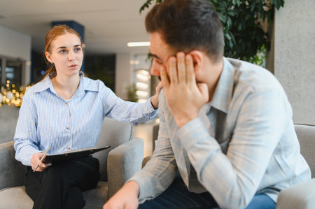 Female therapist providing support and counseling to a distressed male patient experiencing emotional challenges and seeking professional helpの写真素材