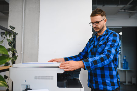 Man placing document on flatbed scanner, working in office, performing tasks like copying, scanning,...