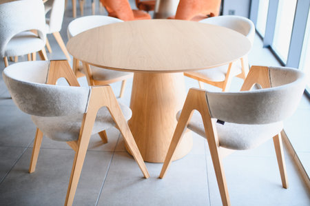 Contemporary minimalist interior design showcasing a stylish wooden round table surrounded by...