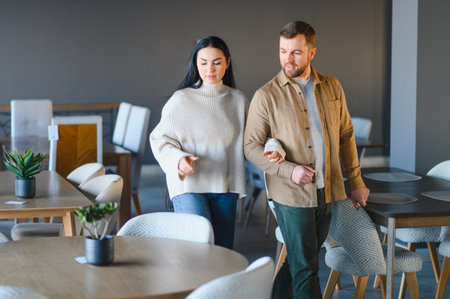 Young couple exploring a furniture store, choosing new pieces for their home while walking among tables and chairsの写真素材