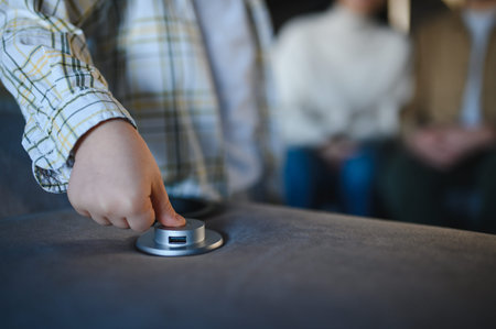 Child's hand pressing a power button and accessing a usb port on a modern sofa, symbolizing home technology and convenienceの写真素材