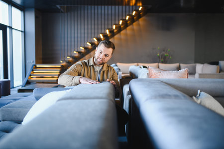 Man touching sofa fabric, evaluating quality and comfort for home improvement. Shopping for new furniture and interior designの写真素材
