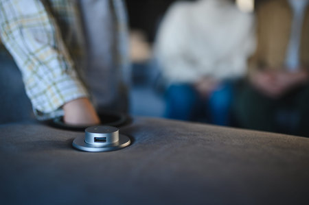 Hand reaching for a modern usb charger integrated into a comfortable upholstered sofa, offering...