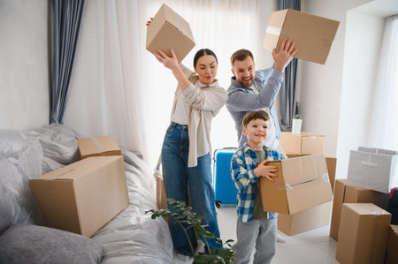 Parents and child enjoying their exciting relocation, carrying cardboard boxes into a new apartment, feeling happiness and successの写真素材