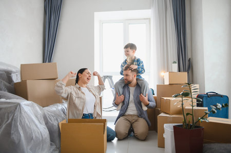 Happy family celebrating an exciting housewarming day in their spacious new apartment, surrounded by cardboard boxesの写真素材