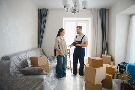 Professional mover talking with a woman, discussing relocation details and signing documents,...