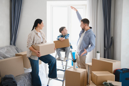 Happy family moving to a new apartment or house, unpacking possessions from storage cartons,...