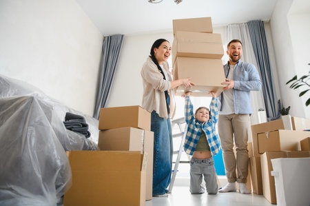 Happy family moving into a new apartment, parents and child handling moving boxes, feeling excited...
