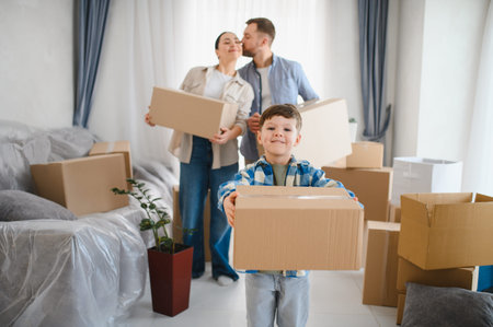 Happy family carrying moving boxes, beginning new life in their apartment. Parents and child relocating togetherの写真素材