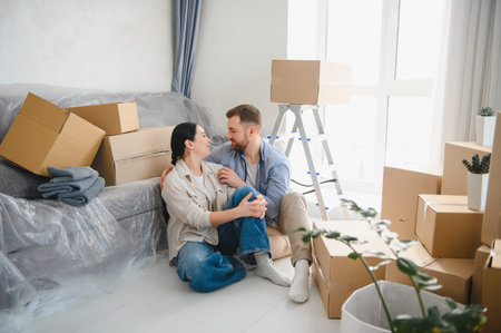 Young couple embracing and looking at each other while taking a break from unpacking cardboard boxes...