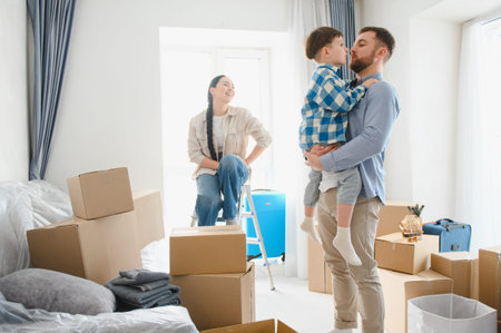 Young family, mother, father and son, unpacking boxes and celebrating moving into new home apartment