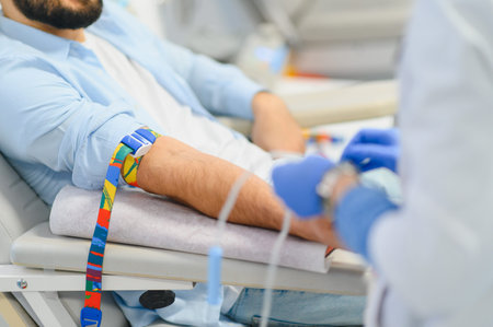 Man donating blood, receiving an intravenous infusion in a clinic. A medical professional preparing...