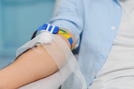 Arm of a person donating blood, connected to medical equipment for transfusion, supporting altruism...