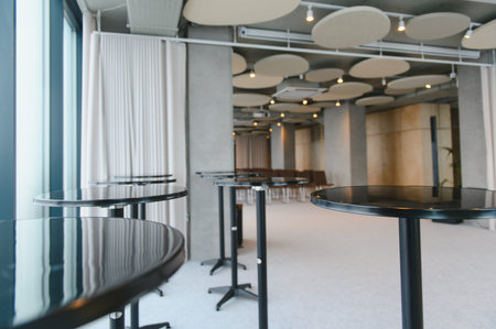 Modern conference hall set up with high cocktail tables and chairs, ready for a corporate networking...