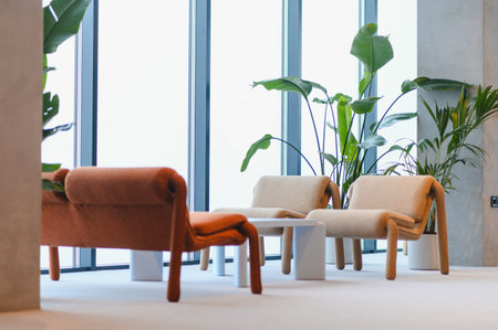 Contemporary seating arrangement with stylish armchairs and green indoor plants creating a...