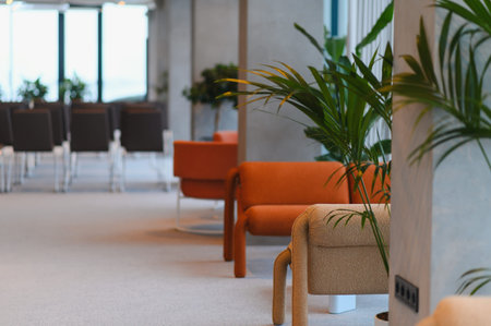 Contemporary corporate interior featuring stylish lounge chairs, green indoor plants, and a light...
