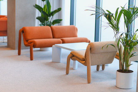 Contemporary corporate lounge area featuring an orange sofa, coordinating armchair, white coffee...