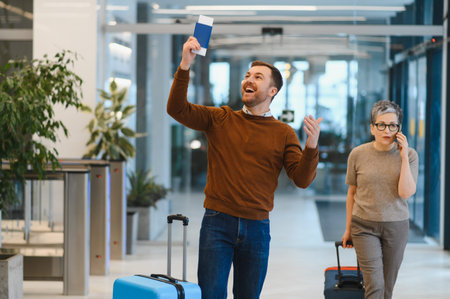 Man joyfully raising passport and boarding pass, ready for vacation, standing in a busy airport terminal
