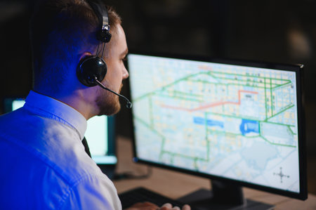 Man wearing a headset dispatching freight and managing transportation while tracking vehicles on a computer map