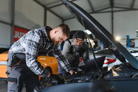 Auto mechanics troubleshooting car engine issues in workshop. Modern vehicle maintenance and repair using diagnostic tools