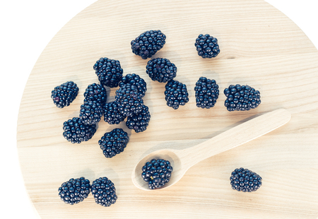 Blackberries on wooden background with wooden spoonの写真素材