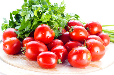 group of red ripe tomatoes and parsley on a wooden boardの写真素材
