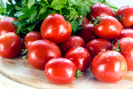 group of red ripe tomatoes and parsley on a wooden boardの写真素材