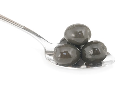 Whole black olives marinated in stainless spoon isolated on white backgroundの写真素材