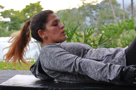 latin woman doing abs in a mat outdoor. High quality photo, horizontal photo.