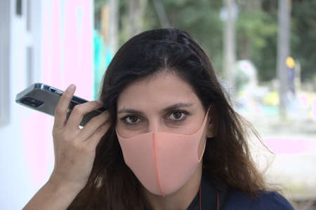latin woman whit pitta mask listening a voice message in the phoneの写真素材