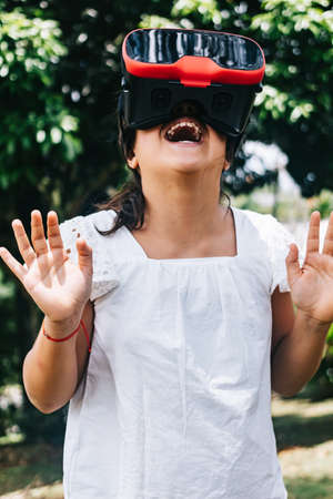 Portrait of pretty little girl enjoying whit her virtual reality glasses in outdoors, VR, Virtual...
