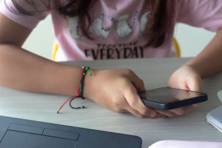 latin girl with phone and laptop in home