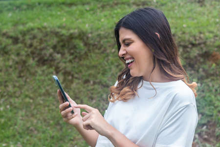 Latina Woman using her mobile phone in outdoors. Fresh airの写真素材