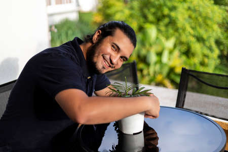 smiling young latino man embracing a pot whit plants. Gardening conceptの写真素材