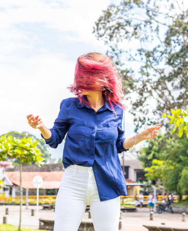 Photo of fluttering colored dyed hair of young woman on sunny city streetの写真素材