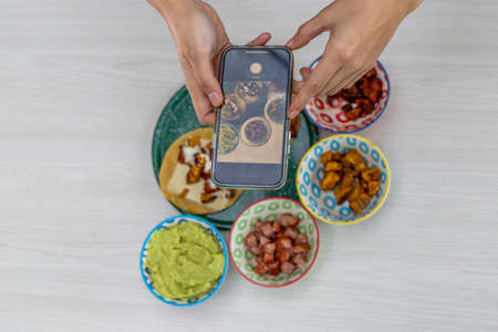 hands with cell phone photographing a freshly prepared mexican meal