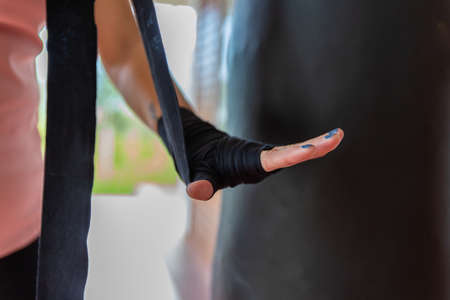 Close up of a unrecognizable woman wrapping her hands with a band, preparing herself for boxing trainingの写真素材