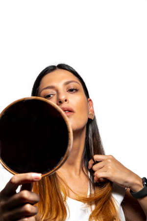 Young latinx Woman Checking Her Hair In Mirror, isolated on white background.の写真素材