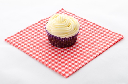 one cupcake buttercream on a red patterned napkin and plateの写真素材